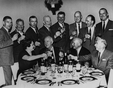 Victor Bergeron toasting the producers of the wines represented on his first major California wine list. Standing (L to R): Karl L. Wente (Wente Brothers), Hanns Kornell (Kornell Champagne), Walter Sullivan (Beaulieu), Louis M. Martini (Louis M. Martini), John Daniel (Inglenook), Fred H. McCrea (Stony Hill), Robert Mondavi (Robert Mondavi Winery), Peter Jurgens (Almaden). Seated (L to R): Dagmar (Mrs. Walter) Sullivan (Beaulieu), Victor Bergeron (Trader Vic), Louis Benoist (Almaden), Otto E. Meyer (Paul Masson).